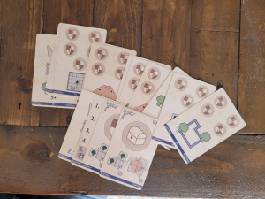12 Auftragskarten, 1 Schatzkarte, 1 Wappenkarte, 1 Spielhilfe